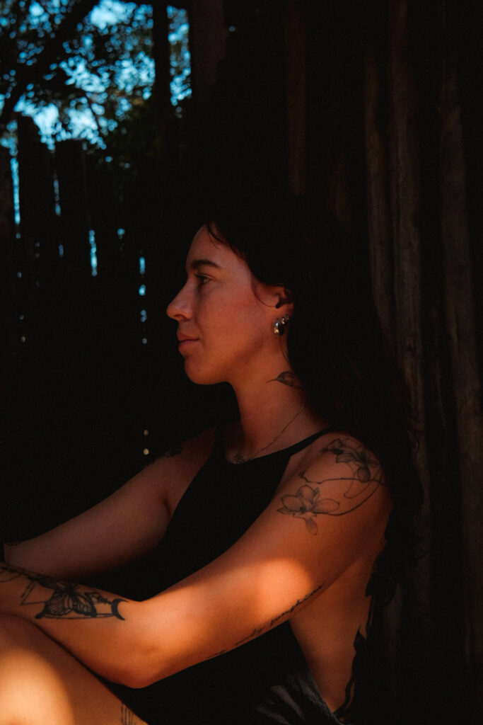 White woman with warm tone lighting in the morning side profile, wearing black backless dress taken with Fujifilm camera for self portrait series for breathwork brand in Europe, London and ibiza