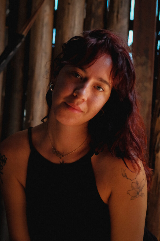 White woman with warm tone lighting in the morning looking directly into Fuji film camera for self portrait series for breathwork brand in Europe, London and ibiza